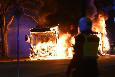 Policías antidisturbios observan el incendio de un autobús urbano en una calle de Malmo, Suecia, el sábado 16 de abril de 2022. (Johan Nilsson/TT vía AP)