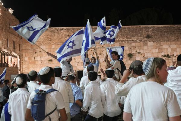 Members of Jewish youth movements dance and wave Israeli flags on the eve of Jerusalem Day an Israeli holiday celebrating the capture of the Old City during the 1967 Mideast war, next to the Western Wall, the holiest site where Jews can pray, in the Old City of Jerusalem, Saturday, May 28, 2022. (AP Photo/Tsafrir Abayov)