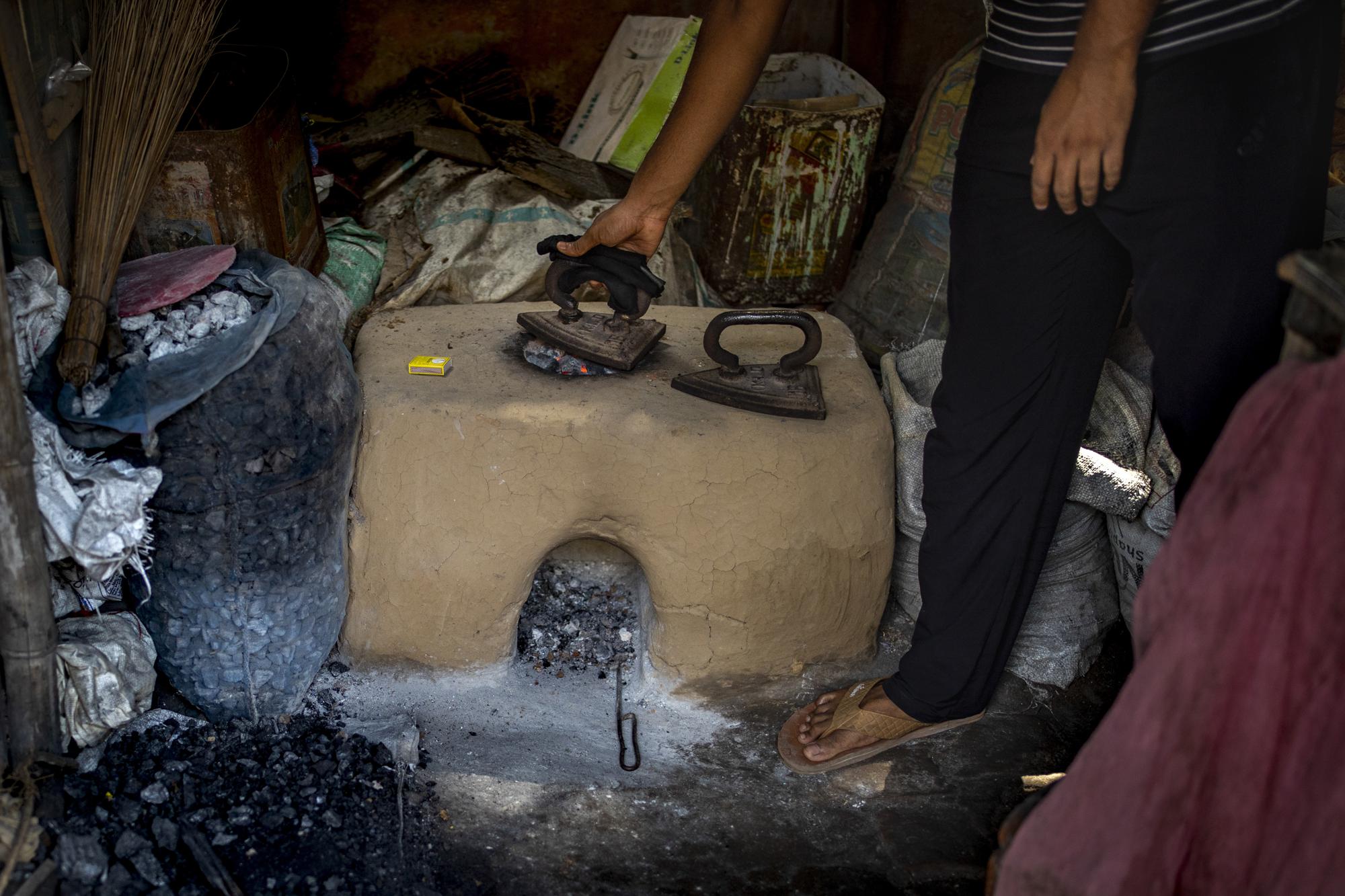 A washerman uses coal to heat up iron in Dhanbad, an eastern Indian city in Jharkhand state, Saturday, Sept. 25, 2021. A 2021 Indian government study found that Jharkhand state -- among the poorest in India and the state with the nation’s largest coal reserves -- is also the most vulnerable Indian state to climate change. Efforts to fight climate change are being held back in part because coal, the biggest single source of climate-changing gases, provides cheap electricity and supports millions of jobs. It's one of the dilemmas facing world leaders gathered in Glasgow, Scotland this week in an attempt to stave off the worst effects of climate change. (AP Photo/Altaf Qadri)