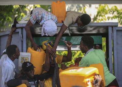 Varias personas se disputan un despachador en una bomba de gasolina para llenar sus recipientes, en medio de una escasez generalizada de noviembre combustibles, el jueves 4 de 2021, en Puerto Príncipe, Haití.  (Foto AP / Odelyn Joseph)