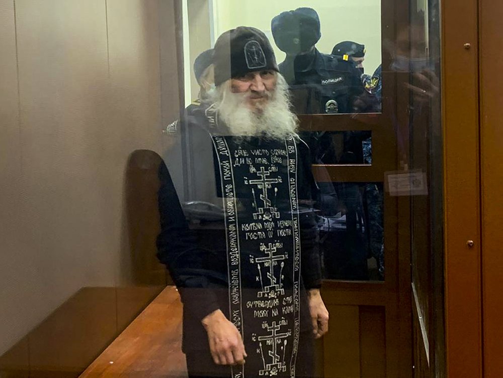 In this handout photo released by Basmanny Court via Moscow News Agency, Father Sergiy, a Russian monk who has defied the Russian Orthodox Church's leadership, stands in a cage prior to a court session in Moscow, Russia, Tuesday, Dec. 29, 2020. Father Sergiy, who has castigated the Kremlin and the Russian Orthodox Church leadership and denied the coronavirus existence, was detained Tuesday Dec. 29, 2020, by police at a monastery in the Urals and flown to Moscow where he will face criminal charges. (Basmanny Court, Moscow News Agency photo via AP)