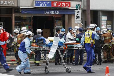 Socorristas acuden con una camilla al incendio de un edificio de ocho pisos en el distrito de negocios, compras y espectáculos en Osaka, Japón, viernes 17 de diciembre de 2021. El siniestro causó 24 muertes. (Yukie Nishizawa/Kyodo News via AP)