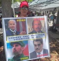 Madelin Munilla, 67, who came to Miami as a child when her parents fled Fidel Castro's Cuba, holds up a sign comparing President Joe Biden to Castro and other Latin American leaders at a rally outside the Wilkie D. Ferguson Jr. U.S. Courthouse, Tuesday, June 13, 2023, in Miami. (AP Photo/Joshua Goodman)