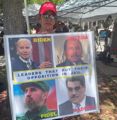 Madelin Munilla, de 67 años, quien llegó a Miami cuando era niña cuando sus padres huyeron de la Cuba de Fidel Castro, sostiene un cartel que compara al presidente Joe Biden con Castro y otros líderes latinoamericanos en un mitin frente al Palacio de Justicia de los Estados Unidos Wilkie D. Ferguson Jr., el martes. , 13 de junio de 2023, en Miami. (Foto AP/Joshua Goodman)