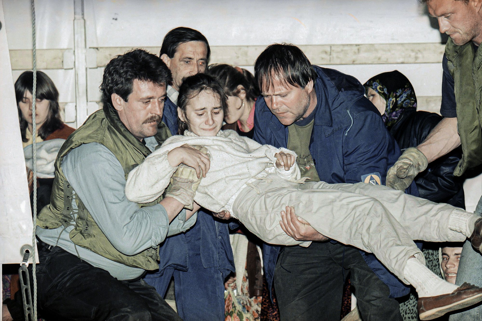 FILE- In this March 20, 1993, file picture, a wounded child form the besieged Bosnian town of Srebrenica is carried off a U.N. truck upon arriving in Tuzla, Bosnia, after a tense journey across the most contested battle lines in Bosnia.  Survivors of the genocide in the eastern Bosnian town of Srebrenica, mainly women, will on Saturday July 11, 2020, commemorate the 25th anniversary of the slaughter of their fathers and brothers, husbands and sons.  At least 8,000 mostly Muslim men and boys were chased through woods in and around Srebrenica by Serb troops in what is considered the worst carnage of civilians in Europe since World War II. The slaughter was also the only atrocity of the brutal war that has been confirmed an act of genocide. (AP Photo/Michel Euler, File)