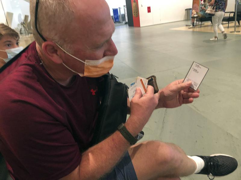 Avner Balkany, 56, of Israel, shows his vaccination card while waiting to enter the Museum of Modern Art in New York on Tuesday, Aug. 17, 2021. He said he was unaware of the city's new vaccination rules but would have nevertheless been prepared to show proof that he was vaccinated in January. (AP Photo/Bobby Caina Calvan)