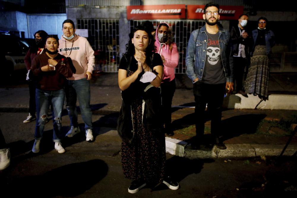 People stand in front of the hotel where U.S. band Foo Fighters' drummer Taylor Hawkins was believed to have been staying, in Bogota, Colombia, Saturday, March 26, 2022. Hawkins, for 25 years the drummer for Foo Fighters and best friend of frontman Dave Grohl, has died during a South American tour with the rock band. He was 50. (AP Photo/Leonardo Munoz)