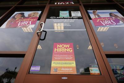 Un letrero de contrataciones abiertas (abajo) se observa en un negocio de bronceado en Richmond, Virginia, el miércoles 2 de junio de 2021. (AP Foto/Steve Helber)