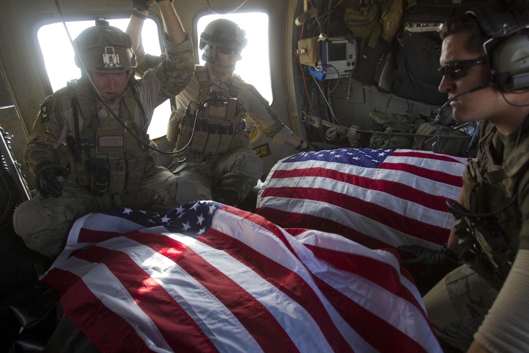 FILE - In this Oct. 10, 2010 file photo, U.S. Air Force pararescue members ride in the back of their medevac helicopter with the American flag draped over bodies of U.S. soldiers who were killed in a roadside bomb attack in Afghanistan's Kandahar province. (AP Photo/David Guttenfelder, File)