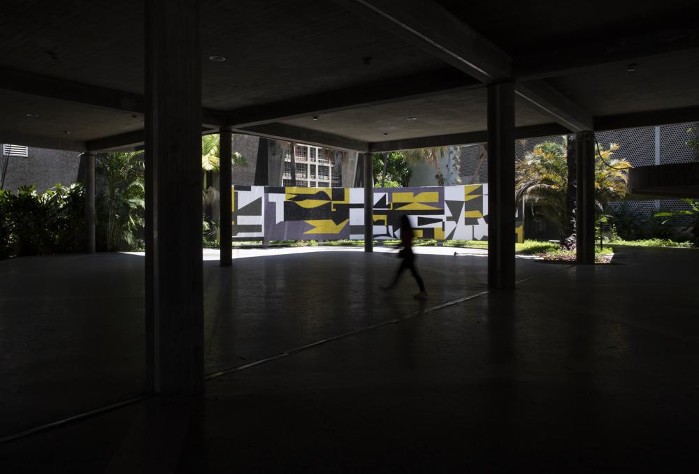 Una persona pasa junto al "Mural Curvo" del artista venezolano Pascual Navarro en la Universidad Central de Venezuela (UCV) en Caracas, Venezuela, el miércoles 7 de julio de 2021.  (AP Foto/Ariana Cubillos)