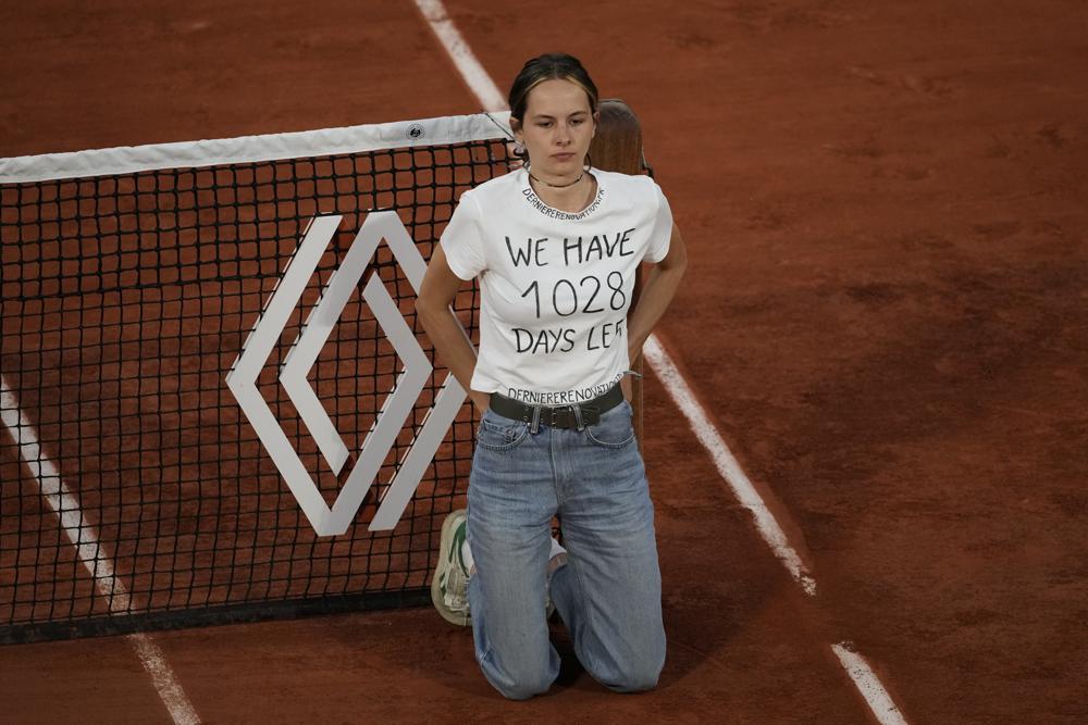 A climate activist ties herself to the net during the semifinal match between Croatia's Marin Cilic and Norway's Casper Ruud at the French Open tennis tournament in Roland Garros stadium in Paris, France, Friday, June 3, 2022. (AP Photo/Thibault Camus)