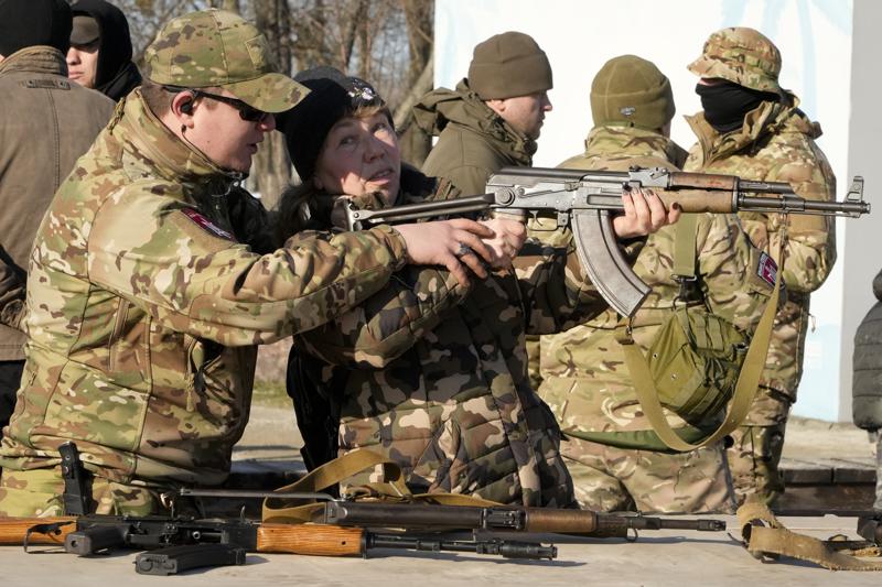 An instructor shows a woman how to use a Kalashnikov assault rifle, as members of a Ukrainian far-right group train, in Kyiv, Ukraine, Sunday, Feb. 13, 2022. Russia denies it intends to invade but has massed well over 100,000 troops near the Ukrainian border and has sent troops to exercises in neighboring Belarus, encircling Ukraine on three sides. U.S. officials say Russia's buildup of firepower has reached the point where it could invade on short notice. (AP Photo/Efrem Lukatsky)