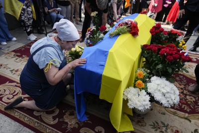 Una mujer se arrodilla junto al féretro del activista y soldado ucraniano Roman Ratushnyi durante su servicio memorial en Kiev el 18 de junio del 2022. Ratushnyi murió en una batalla cerca de Izyum, donde tropas rusas y ucranianas pelean por el control del área. (AP Foto/Natacha Pisarenko)