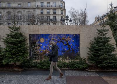 Una mujer usa mascarilla mientras pasa frente a decoraciones navideñas en París, el domingo 26 de diciembre de 2021. (AP Foto/Rafael Yaghobzadeh)