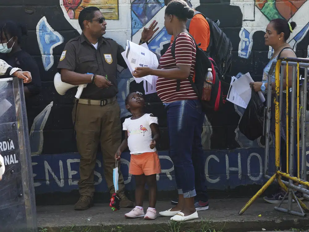 Un funcionario comprueba los documentos de migrantes que esperan para regularizar su situación en México frente al Instituto Nacional de Migración de Tapachula, estado de Chiapas, México, el martes 4 de octubre de 2022. La estrategia de México ha sido administrar el imparable número de llegadas facilitando ciertos permisos sin criterios claros. Los migrantes llaman popularmente a casi todos estos documentos “salvoconductos”. (AP Foto/Marco Ugarte)