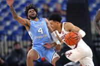 North Carolina guard R.J. Davis (4) fouls Alabama guard Jahvon Quinerly during the first half of an NCAA college basketball game in the Phil Knight Invitational on Sunday, Nov. 27, 2022, in Portland, Ore. (AP Photo/Rick Bowmer)