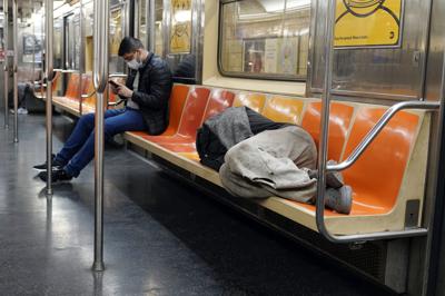 ARCHIVO - Un hombre duerme en los asientos del tren subterráneo, en Nueva York, el 14 de abril de 2021.El alcalde de Nueva York, Eric Adams, está anunciando un plan para aumentar la seguridad en la extensa red de metro de la ciudad y tratar de evitar que las personas sin hogar duerman en trenes o vivan en estaciones. (AP Photo/Richard Drew, Archivo)