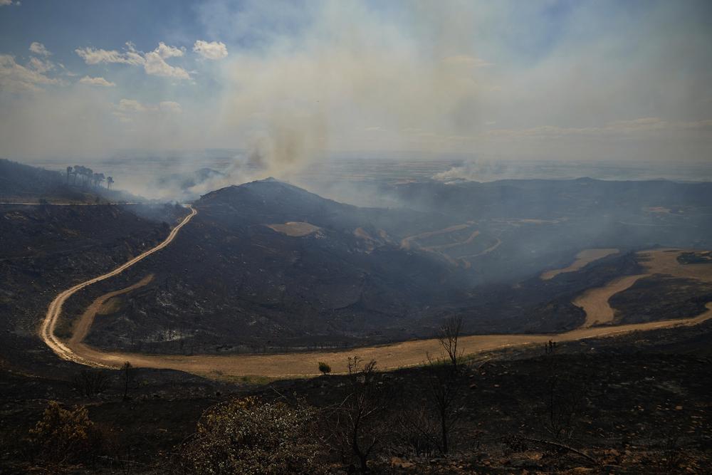 Smoke rises from the hills in Ujue, northern Spain, Sunday, June 19, 2022. Firefighters in Spain are struggling to contain wildfires in several parts of the country which as been suffering an unusual heat wave for this time of the year. (AP Photo/Miguel Oses)