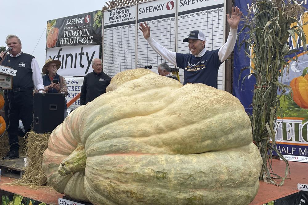 Travis Gienger from Anoka, Minn., stands behind his winning pumpkin at the 49th World Championship Pumpkin Weigh-Off in Half Moon Bay, Calif., Monday, Oct. 10, 2022. AP Photo/Haven Daley)