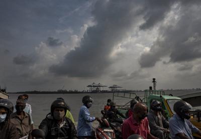 Nubes cargadas de lluvia se ven en el horizonte mientras unas personas viajan en ferry en Kochi, Kerala, India, el 18 de octubre de 2021. (AP Foto/R S Iyer)