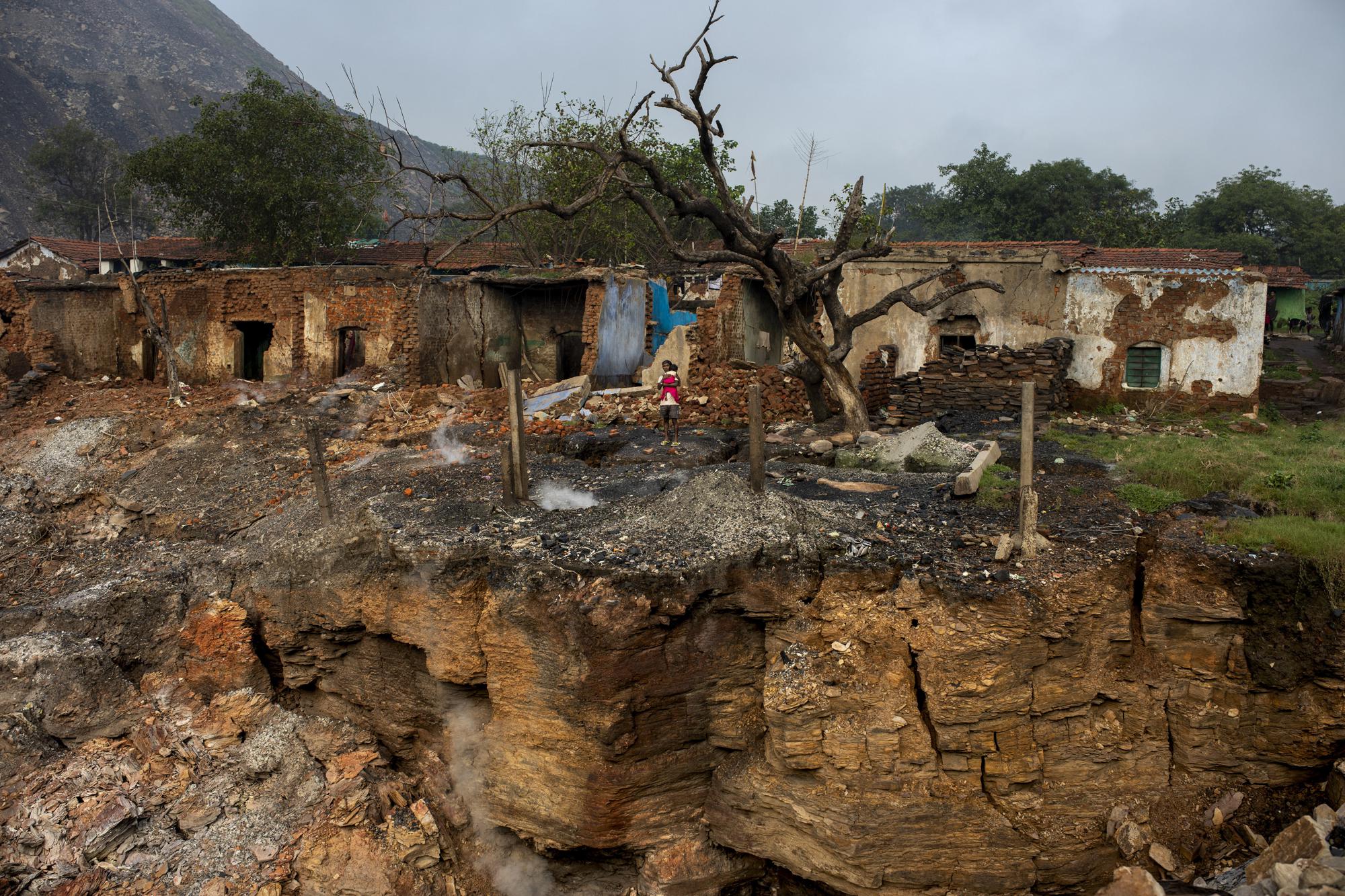 Smoke hisses from the cracks in the ground as a villager holds his child in front of houses damaged due to subsidence near Dhanbad, an eastern Indian city in Jharkhand state, Friday, Sept. 24, 2021. A 2021 Indian government study found that Jharkhand state -- among the poorest in India and the state with the nation’s largest coal reserves -- is also the most vulnerable Indian state to climate change. Efforts to fight climate change are being held back in part because coal, the biggest single source of climate-changing gases, provides cheap electricity and supports millions of jobs. It's one of the dilemmas facing world leaders gathered in Glasgow, Scotland this week in an attempt to stave off the worst effects of climate change. (AP Photo/Altaf Qadri)