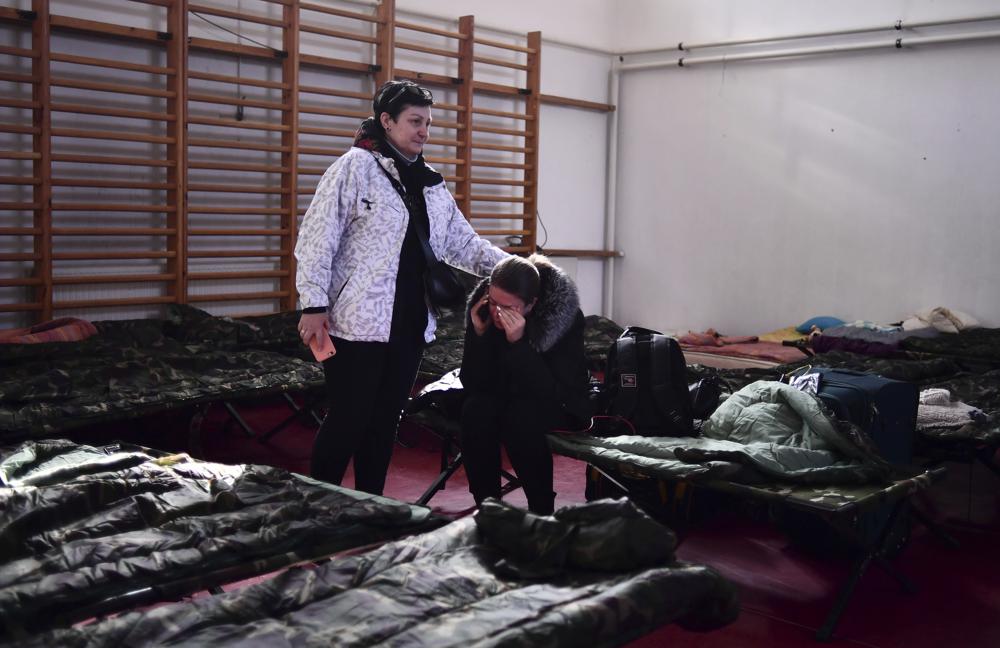 Một phụ nữ an ủi một người khác tại nơi trú ẩn tạm thời được thiết lập cho những người di tản chạy trốn khỏi Ukraine ở Beregsurany, Hungary. Ảnh AP / Anna Szilagyi.