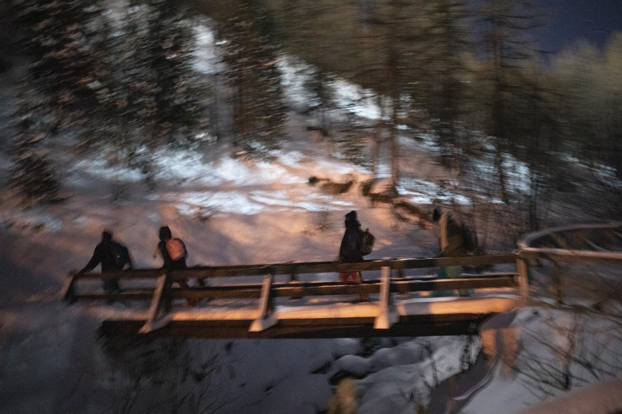 Migrants leave the Italian border town of Claviere in an attempt to cross into France at night on Saturday, Dec. 11, 2021. (AP Photo/Daniel Cole)