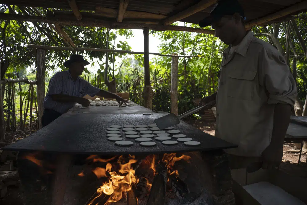 Julio Cesar Nunez und sein Neffe Agustin bereiten Casabe über einem Holzfeuer, in Quivican, Kuba, 28.05.23 | Bildquelle: AP © AP Photo/Ramon Espinosa | Bilder sind in der Regel urheberrechtlich geschützt