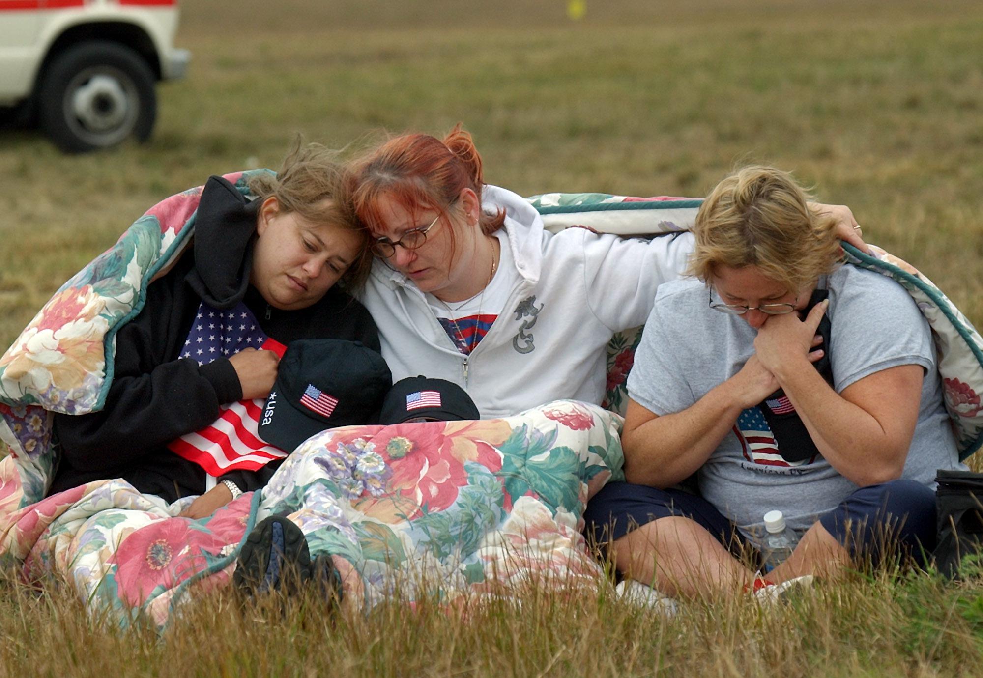 ADVANCE FOR PUBLICATION ON SUNDAY, SEPT. 5, AND THEREAFTER - FILE - In this Wednesday, Sept. 11, 2002 file photo, from left, Shannon Barry, Lisa Starr and Michelle Wagner, all of Hershey, Pa., comfort each other as they listen to a memorial service for victims of Flight 93 near Shanksville, Pa. President Bush will lay a wreath at the crash site later in the day to mark the anniversary of the terrorist attacks. (AP Photo/Julie Jacobson, File)