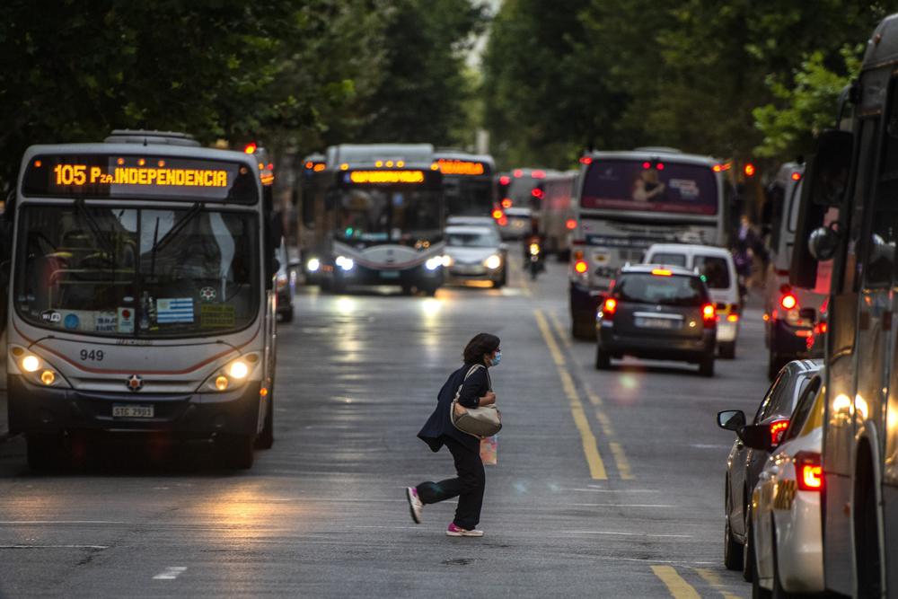 ARCHIVO - En esta fotografía de archivo del 16 de marzo de 2021, una mujer con una máscara para frenar la propagación del nuevo coronavirus cruza la avenida principal de Montevideo, Uruguay. (AP Foto/Matilde Campodonico, Archivo)