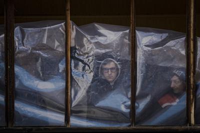 La gente colocó láminas de plástico para cubrir las ventanas rotas de sus apartamentos después de que partes de un misil ruso, derribado por la defensa aérea ucraniana, aterrizaran en un bloque de apartamentos, según las autoridades, en Kiev, Ucrania, el jueves 17 de marzo de 2022. Las fuerzas rusas destruyeron un teatro en Mariupol donde cientos de personas se refugiaban el miércoles y dispararon sobre otras ciudades, dijeron las autoridades ucranianas, incluso cuando las dos partes proyectaron optimismo sobre los esfuerzos para negociar el fin de los combates. (AP Foto/Vadim Ghirda)