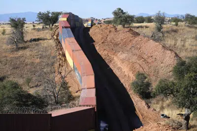 Una larga hilera de contenedores encimados proporciona un muro provisional en la frontera entre Estados Unidos y México, el jueves 8 de diciembre de 2022, en el remoto Valle de San Rafael, Arizona. (AP Foto/Ross D. Franklin)