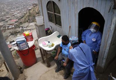 Una enfermera le da una inyección de la vacuna Sinopharm COVID-19 a Wilber Guzmán en su casa, durante una campaña de vacunación casa por casa en el barrio Villa María del Triunfo de Lima, Perú, el miércoles 13 de octubre de 2021. (AP Foto/Martín Mejía)