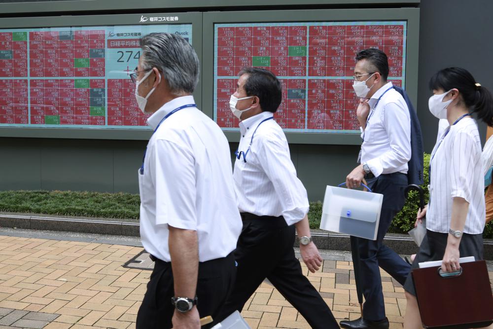 People walk by an electronic stock board of a securities firm in Tokyo, Monday, Aug. 23, 2021. Asian shares rose Monday as investor sentiment received a big boost from the rally last week on Wall Street, despite worries about the more contagious coronavirus delta variant not only in the region but across the world. (AP Photo/Koji Sasahara)