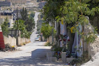 Flores, banderas y otros recuerdos crean un monumento improvisado en el sitio donde la veterana reportera palestino-estadounidense Shireen Abu Akleh fue asesinada a tiros, en la ciudad cisjordana de Jenin, el 19 de mayo de 2022. Casi dos semanas después de la muerte de Abu Akleh, una reconstrucción de The Associated Press respalda las afirmaciones tanto de las autoridades palestinas como de los colegas de Abu Akleh de que la bala que la atravesó provino de un arma israelí. (AP Photo/Majdi Mohammed)