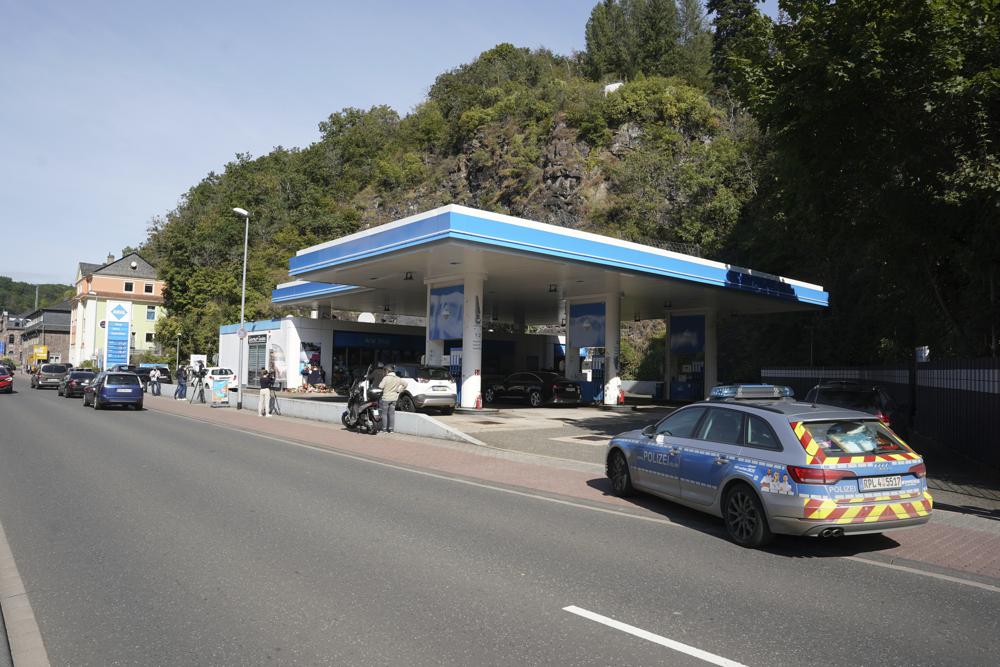 Medien und ein Polizeiauto stehen vor einer Tankstelle in Idar-Oberstein, Deutschland, Dienstag, 21. September 2021. Die Polizei in Deutschland teilt mit, dass ein 49-jähriger Mann wegen Mordverdachts im Zusammenhang mit der Tötung festgenommen wurde des Tankstellenmitarbeiters, der am Samstag nach einem Streit um Gesichtsmasken an der Tankstelle erschossen wurde. (Thomas Frey/dpa via AP)