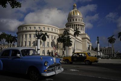 Un antiguo automóvil Lada de fabricación rusa, a la derecha, y un automóvil clásico de fabricación estadounidense pasan frente al Capitolio en La Habana, Cuba, el viernes 1 de abril de 2022. (AP Foto/Ramón Espinosa)