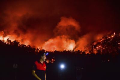 Un hombre se marcha ante el avance de los incendios en la zona de Hisaronu, Turquía, el lunes 2 de agosto de 2021. Los bomberos turcos seguían el martes con su lucha de toda una semana contra los incendios en bosques y pueblos de la costa sur del país, mientras el gobierno recibía crecientes críticas por su aparente mala gestión y su preparación inadecuada para los grandes fuegos. (AP Foto)