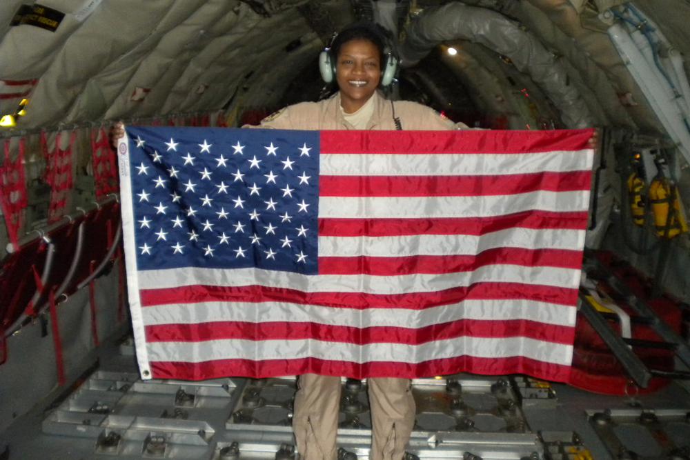 In this Dec. 28, 2009 photo provided by Retired Air Force Lt. Col. Stephanie Davis, she holds a U.S. flag in the cargo area of a KC-135 airplane while flying over Pakistan/Afghanistan. For Davis, who grew up poor, the military was a path to the American dream, a realm where everyone would receive equal treatment. But many of her service colleagues, Davis says, saw her only as a Black woman. Or for the white resident colleagues who gave her the call sign of ABW – it was a joke, they insisted – an “angry black woman,” a classic racist trope. (Courtesy Stephanie Davis via AP)