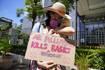 Una activista muestra un cartel con una muñeca que representa a los bebés afectados por la contaminación aérea, durante una protesta ante la Corte del Distrito Central de Yakarta, donde se dirimía una demanda contra autoridades indonesias por no mejorar la calidad del aire, el 16 de septiembre de 2021. El cartel dice "La polución aérea mata (especialmente) bebés". (AP Foto/Dita Alangkara)