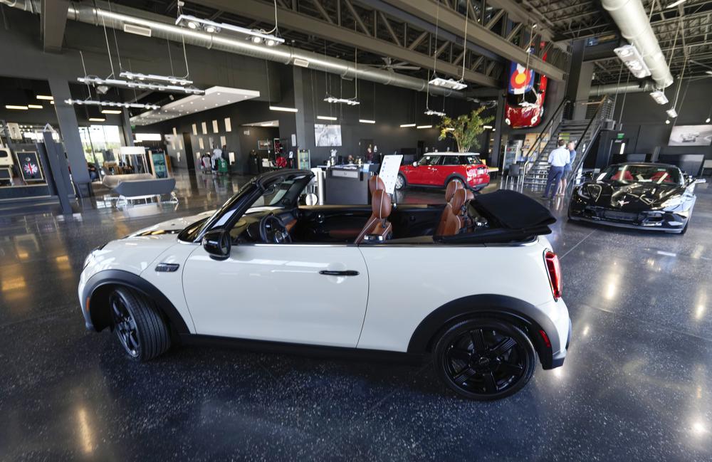 FILE - A sales associate talks with a prospective buyer of a Cooper SE electric vehicle on the showroom floor of a Mini dealership July 7, 2022, in Highlands Ranch, Colo. The surprise deal by Senate Democrats on a pared-down bill to support families, boost infrastructure and fight climate change is likely to jump start sales of electric vehicles. (AP Photo/David Zalubowski, File)