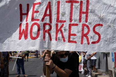 Una persona sostiene una pancarta durante una manifestacion de trabajadores de la salud en Atenas, Grecia, el 26 de agosto de 2021. (AP Foto/Thanassis Stavrakis)