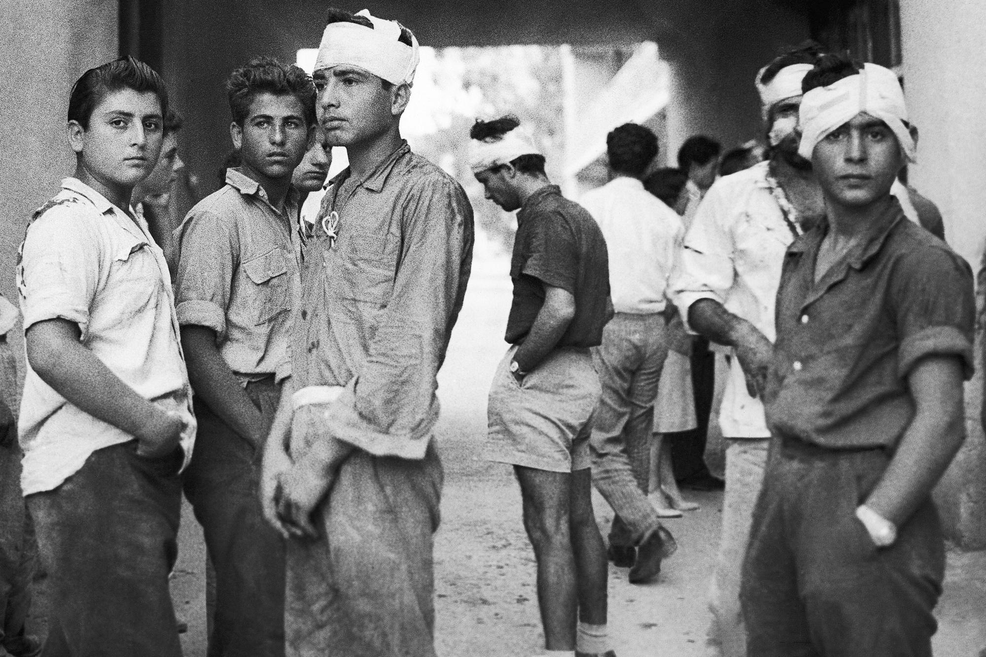 Greek Cypriot youths, some with bandaged heads, stand outside a hospital in Famagusta, Cyprus, on Oct. 4, 1958. They said their injuries were received in the intensive round up operations conducted by security forces the day after EOKA terrorists shot dead one British woman and injured another as they left a shop on Hermes Street in Famagusta. (AP Photo, File)