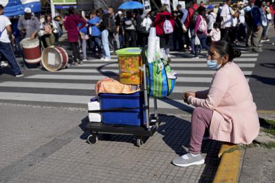Una vendedora de frutas se sienta en una acera mientras espera clientes durante una manifestación en reclamo de más empleo y asistencia social en Buenos Aires, Argentina, el miércoles 13 de abril de 2022. (AP Foto/Natacha Pisarenko)