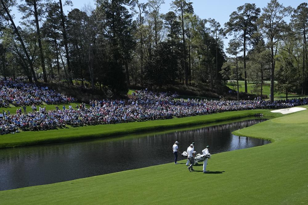Cameron Smith, de Australia, y Bryson DeChambeau, a la derecha, caminan por la calle 16 con sus caddies durante la primera ronda del torneo de golf Masters el jueves 7 de abril de 2022 en Augusta, Georgia (AP Photo/David J. Phillip )