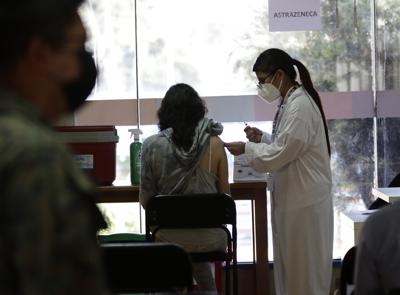 Una mujer recibe su vacuna contra el COVID-19 en Quito, Ecuador, el jueves 23 de diciembre de 2021. El gobierno de Ecuador suspendió el viernes 7 de enero de 2022 las clases en el sistema público y aceleró la vacunación de los docentes ante la aceleración en los contagios en la población infantil. (AP Foto/Carlos Noriega)