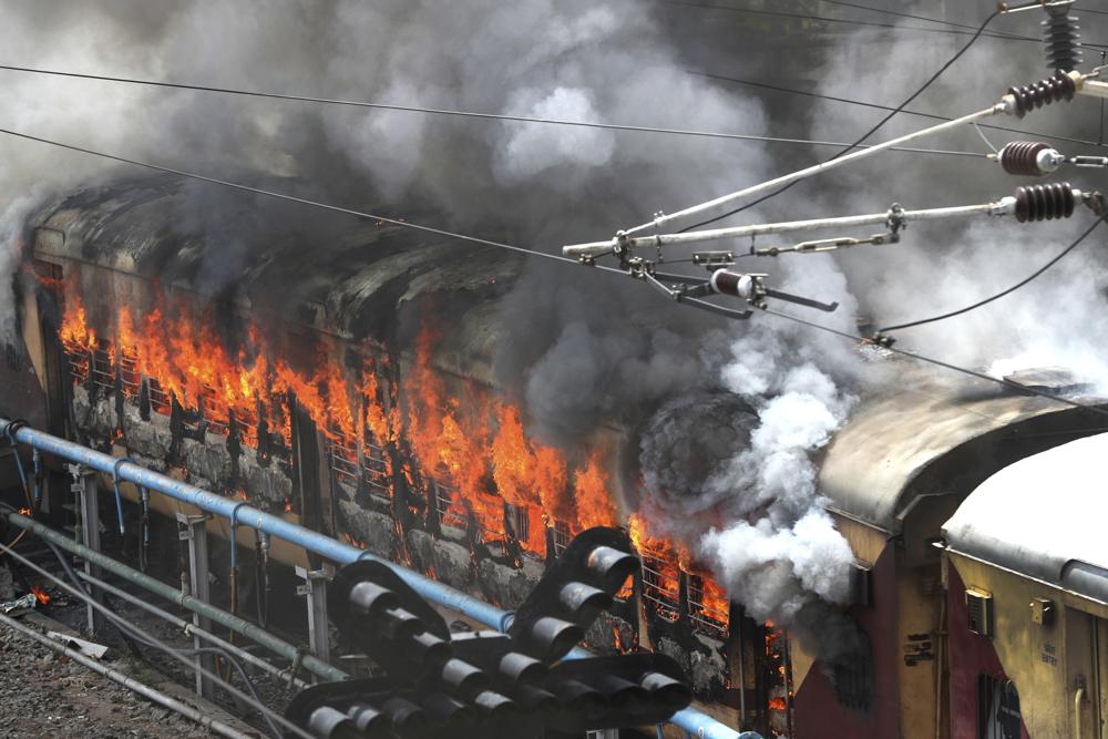 Flames rise from a train set on fire by protestorsat Secundrabad railroad station in Hyderabad, India, Friday, June 17, 2022. Hundreds of angry youths gave vent to their ire by burning train coaches, vandalizing railroad property and blocking rail tracks and highways with boulders as a backlash continued for a second straight day Friday against a new short-term government recruitment scheme for the military. Nearly 500 protesters vastly outnumbered policemen as they went on a rampage for more than an hour at Secundrabad railroad station in southern India.