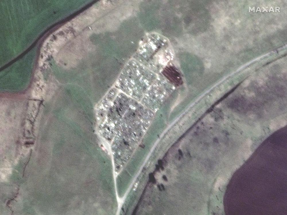 This satellite image provided by Maxar Technologies shows an expansion of graves at a cemetery near Vynohradne, approximately 12 kilometers east of Mariupol, Ukraine, on April 15, 2022. From mid-March through mid-April, there are new excavations at Vynohradne that consist of parallel trenches, with each trench approximately 40-meters long. (Satellite image ©2022 Maxar Technologies via AP)