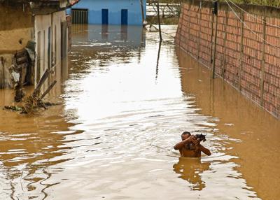 Un hombre carga a su perro en una calle inundada en Itapetinga, estado de Bahia, Brasil, el lunes 27 de diciembre de 2021. (AP Foto/Manuella Luana)