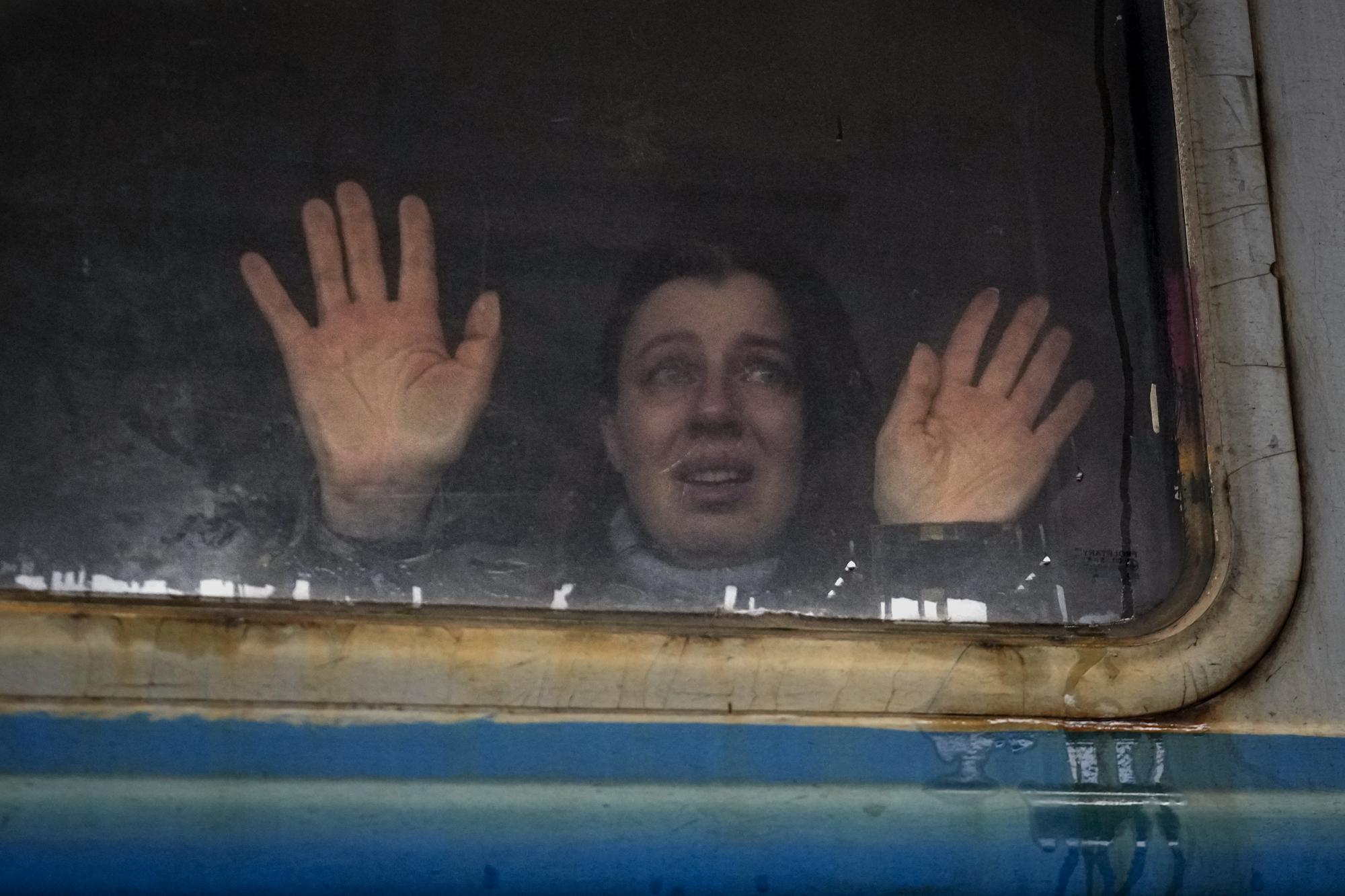 A woman looks toward relatives and presses her palms against a window of a Lviv bound train, on the platform in Kyiv, Ukraine, Thursday, March 3, 2022. (AP Photo/Vadim Ghirda)